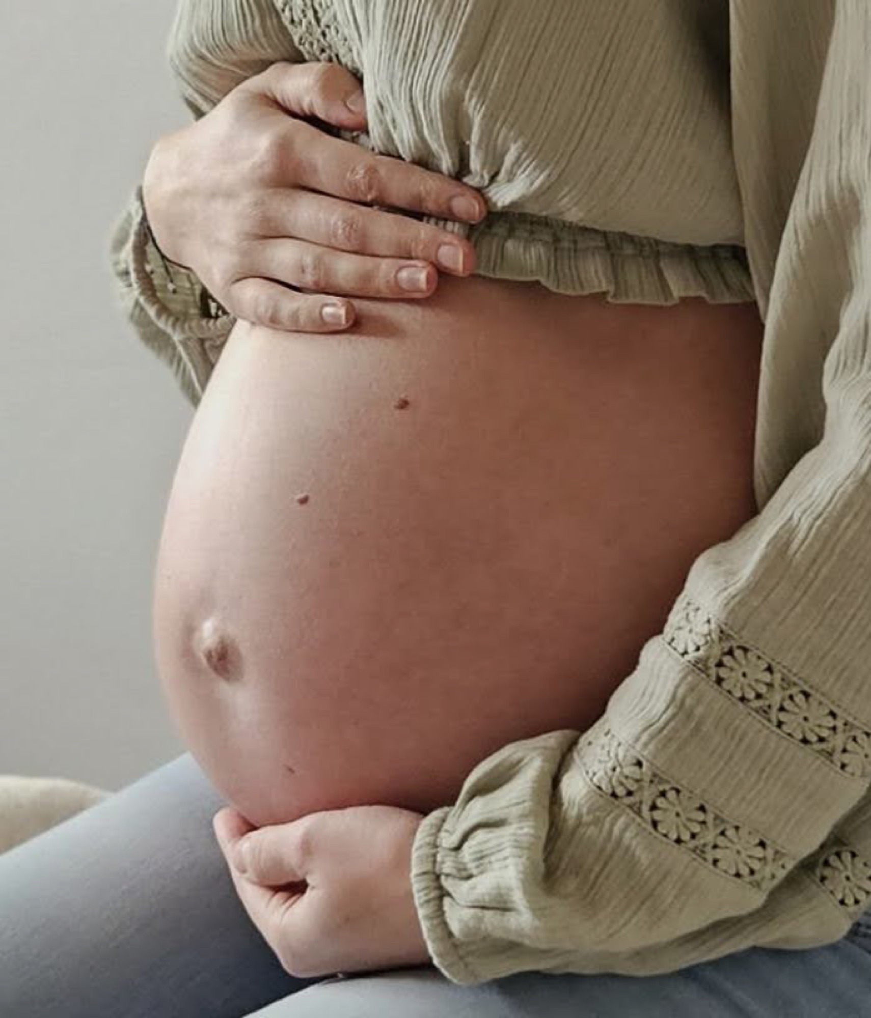 Werdende Mutter umfasst sanft ihren Babybauch